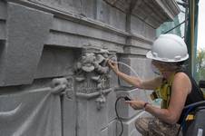 L'image montre une restauratrice effectuant le nettoyage des chapiteaux de la tour de l'Assemblée nationale du Québec