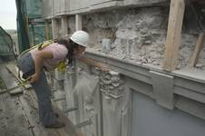 La photo montre une restauratrice effectuant l'évaluation des travaux de réfection de la maçonnerie de la tour du Parlement.