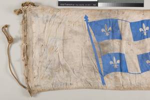 Gros plan sur une partie de la banderole présentant le drapeau imprimé et les bords abîmés, avant restauration.